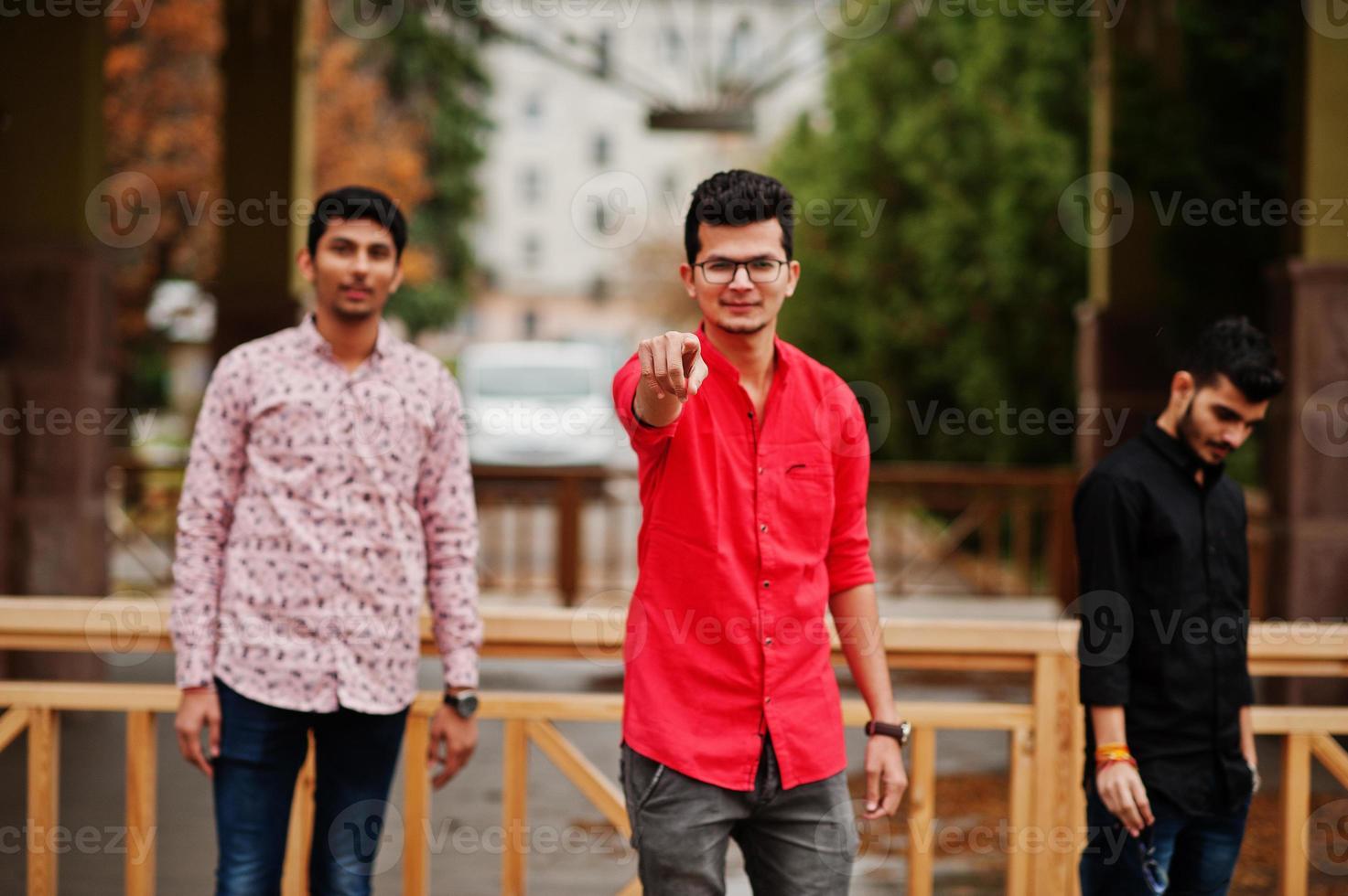 Three indian guys students friends posed on street, one of men show finger. photo