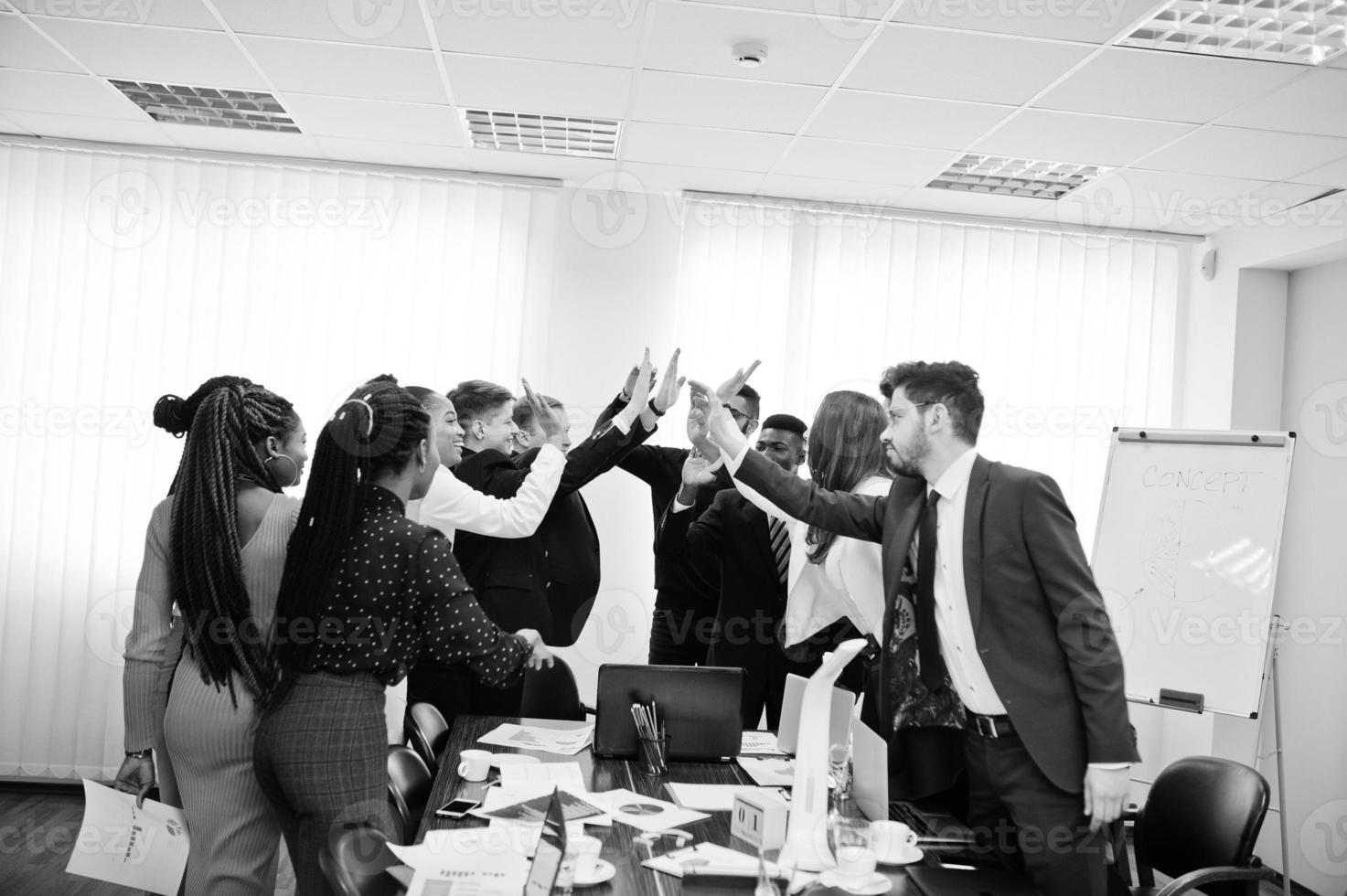 Multiracial business people standing at office and give high five each other. Diverse group of employees in formal wear. photo