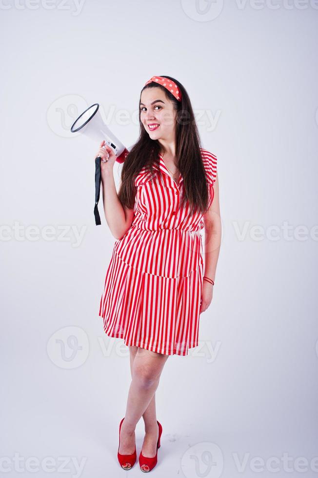 Portrait of a young beautiful woman in red dress talking into megaphone. photo