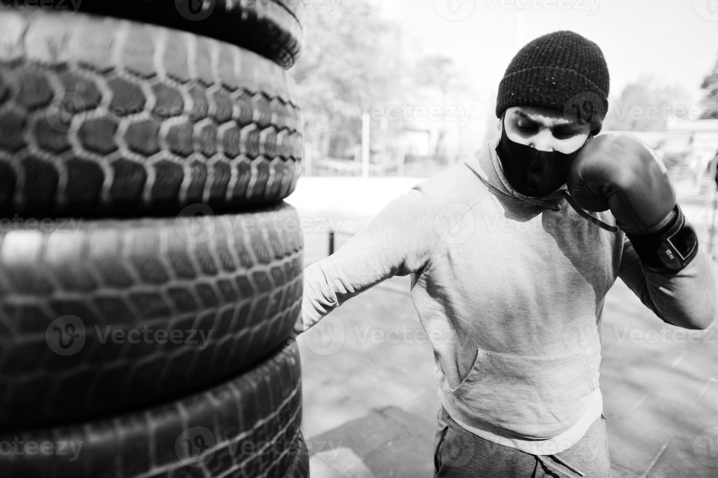 Portrait sports arabian boxer man in black medical face mask boxing outdoor during coronavirus quarantine. photo