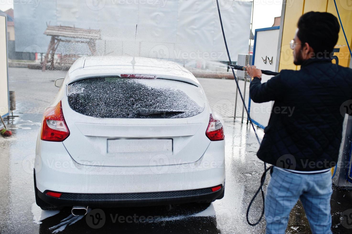 hombre del sur de asia o hombre indio lavando su transporte blanco en el lavado de autos. foto