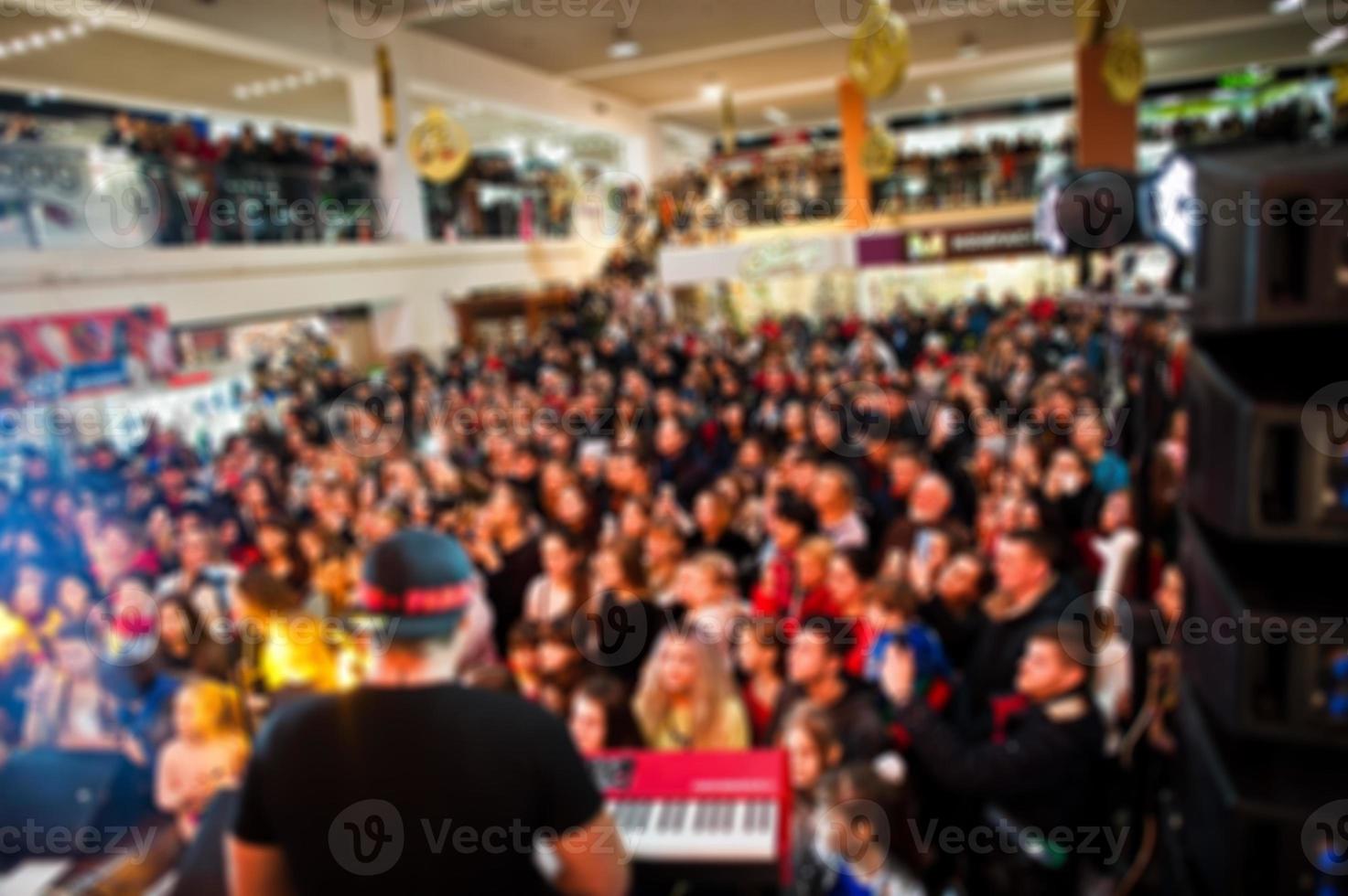 Blured photo crowded concert hall with scene stage lights with people at rock performance.