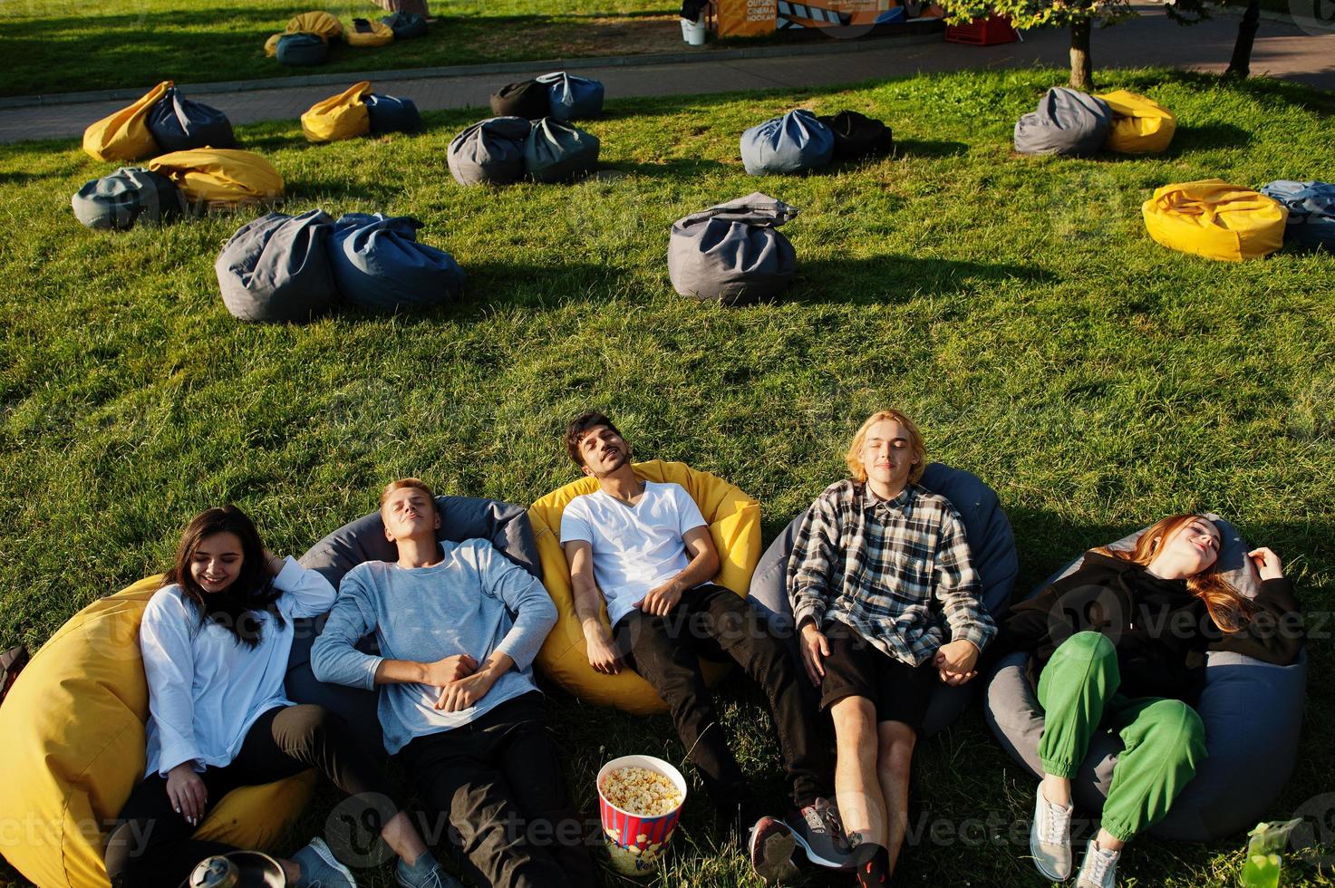 Young multi ethnic group of people watching movie at poof in open air cinema. photo