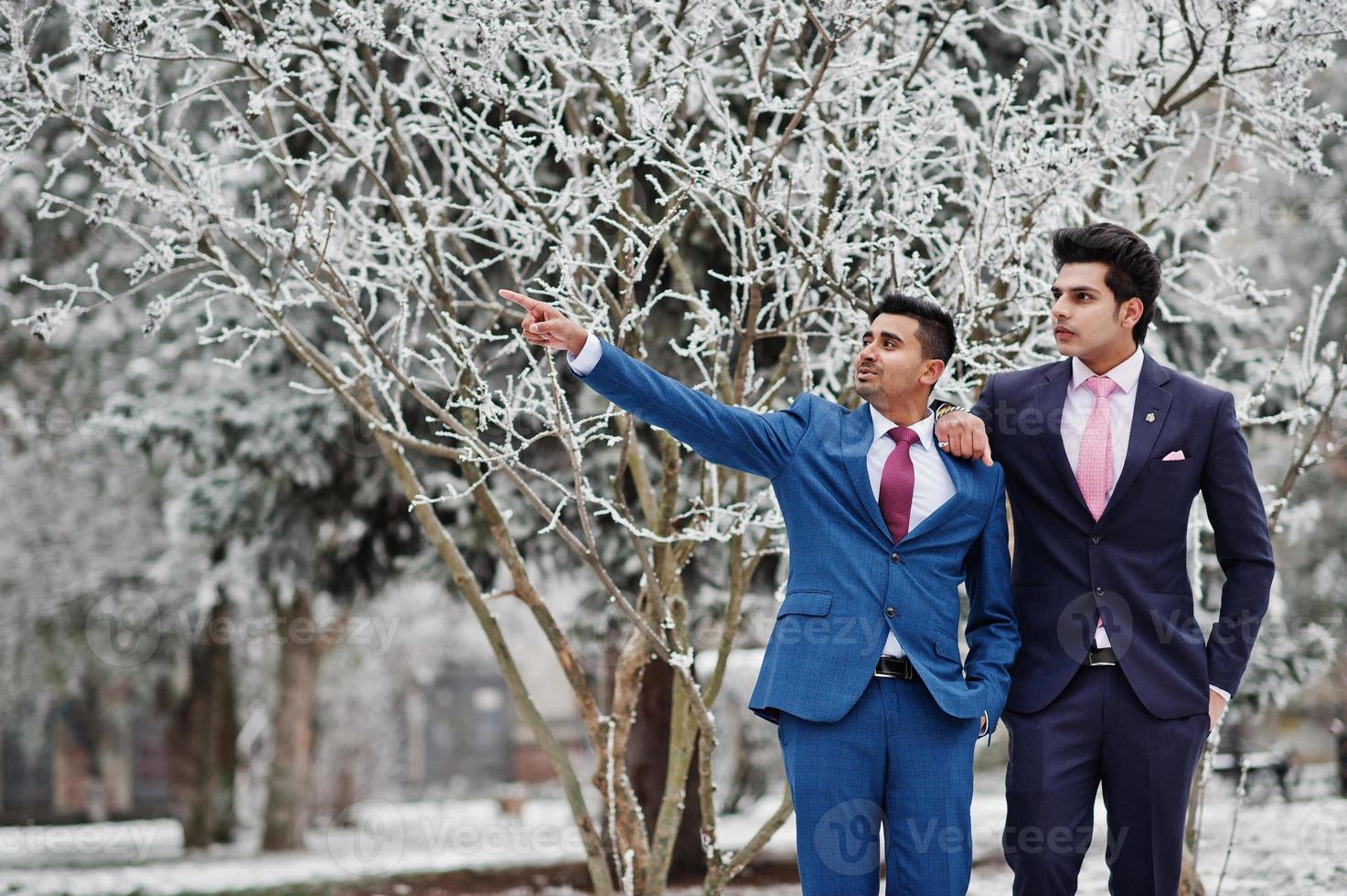 dos elegantes modelos indios de moda en traje posaron en el día de invierno, muestran algo. foto