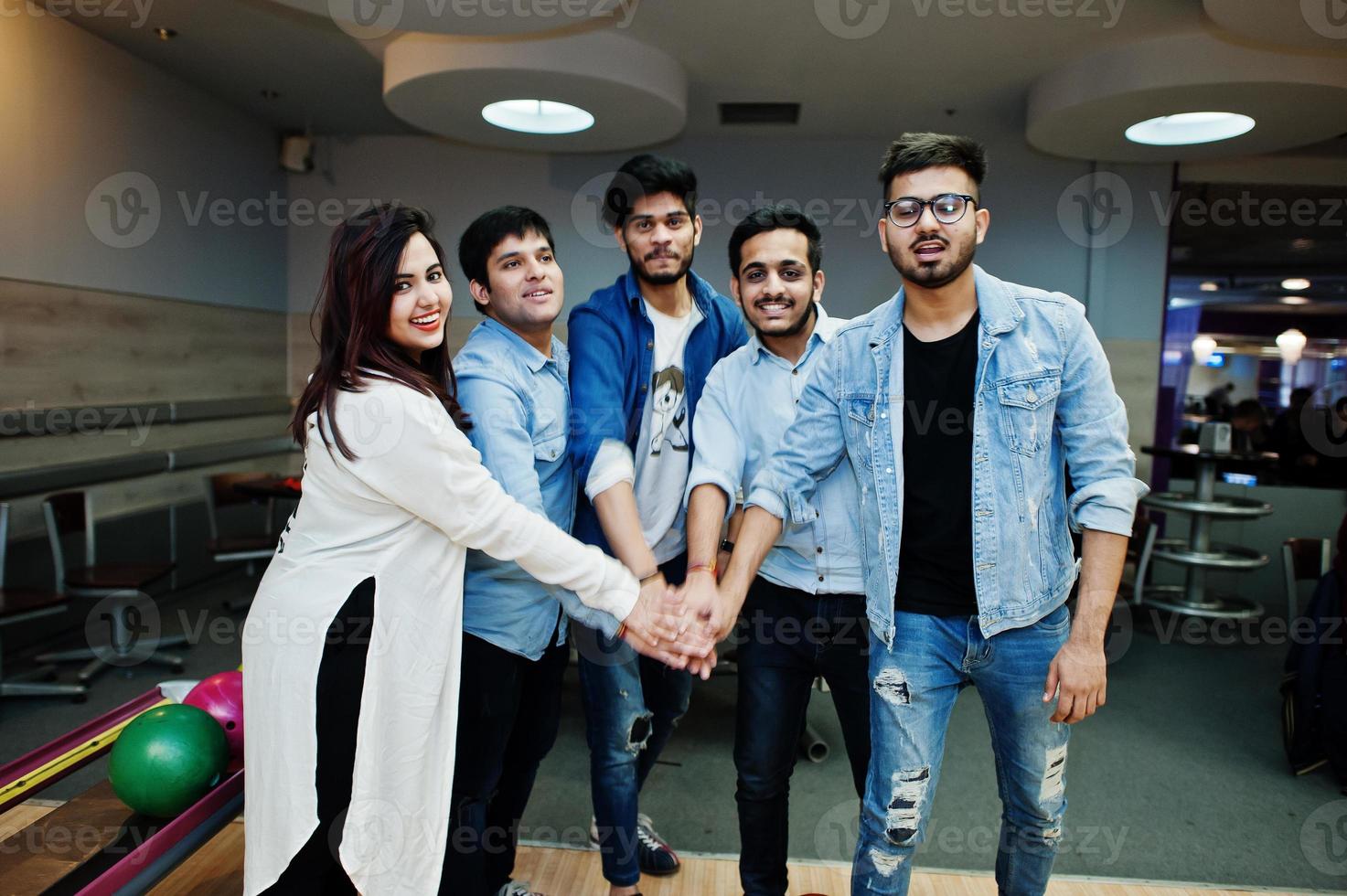 Group of five south asian peoples having rest and fun at bowling club. Putting their hands together, friends showing unity and teamwork. photo