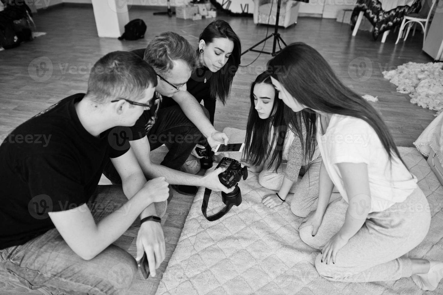 The team of photographers showing pictures on screen of camera for twins models girls on studio. Professional photographer on work. photo