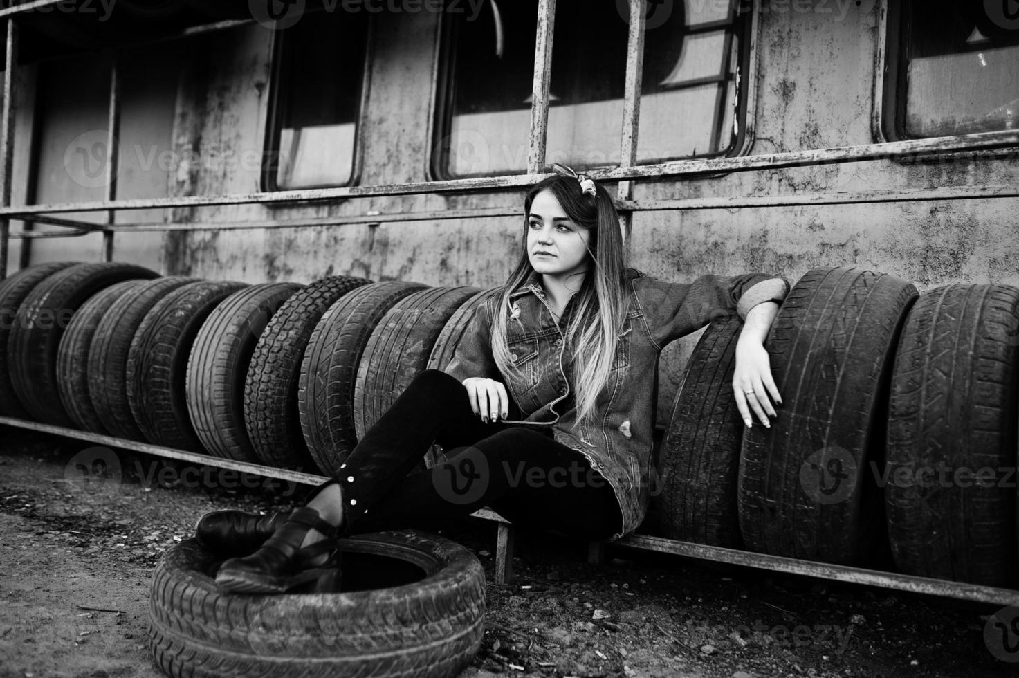 Young hipster girl in jeans jacket and head scarf at tire fitting zone. photo