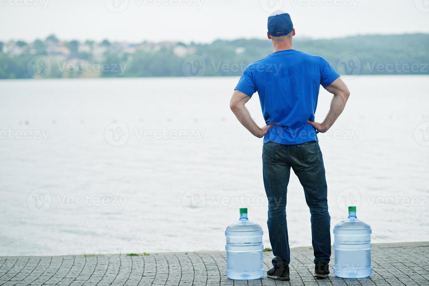 Back of delivery man with water bottles at hands. photo