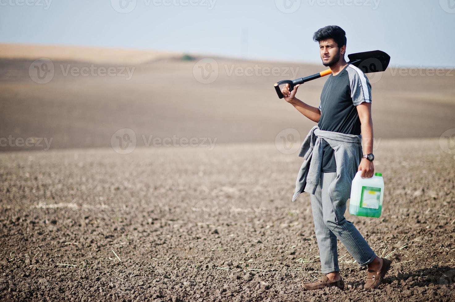 South asian agronomist farmer with shovel inspecting black soil. Agriculture production concept. photo