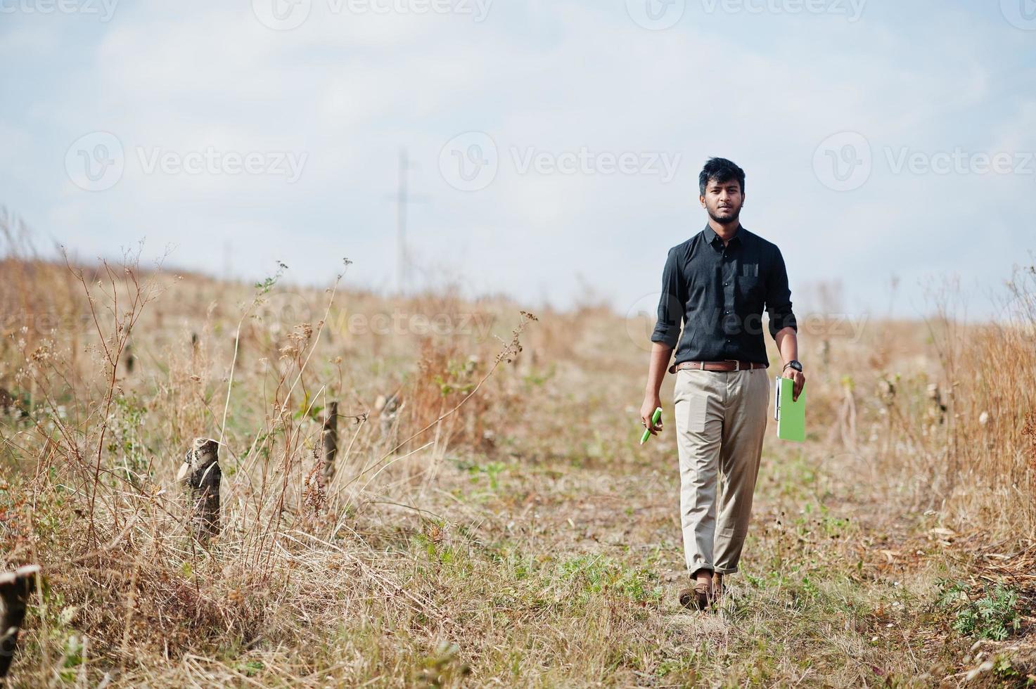 South asian agronomist farmer with clipboard inspecting cut trees in the farm garden. Agriculture production concept. photo