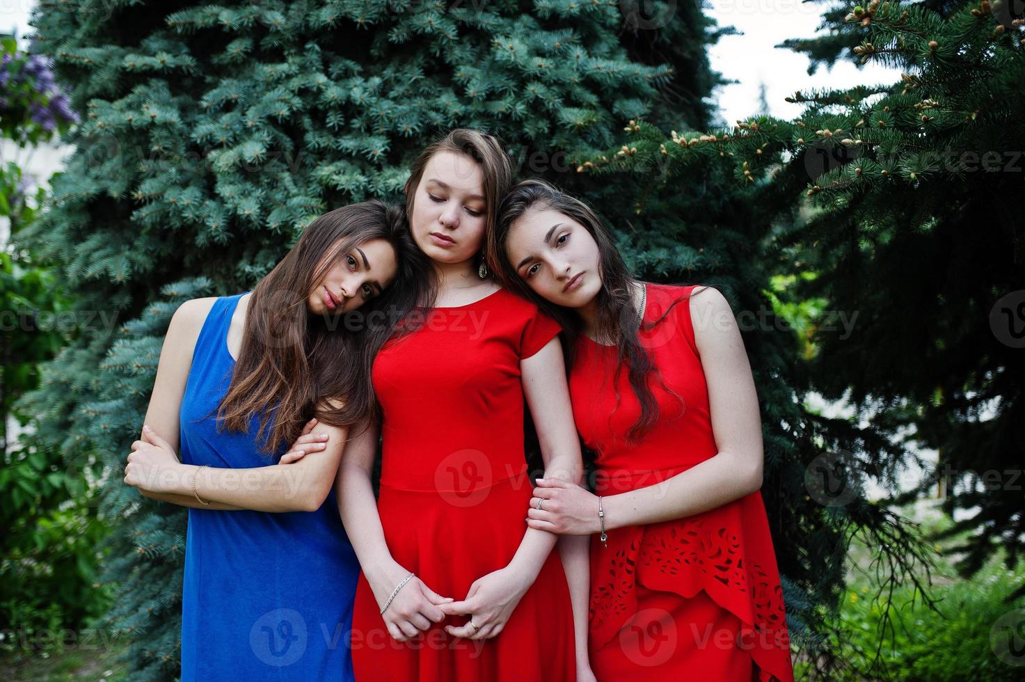 Three teenagers girl in blue and red dresses posed outdoor. photo