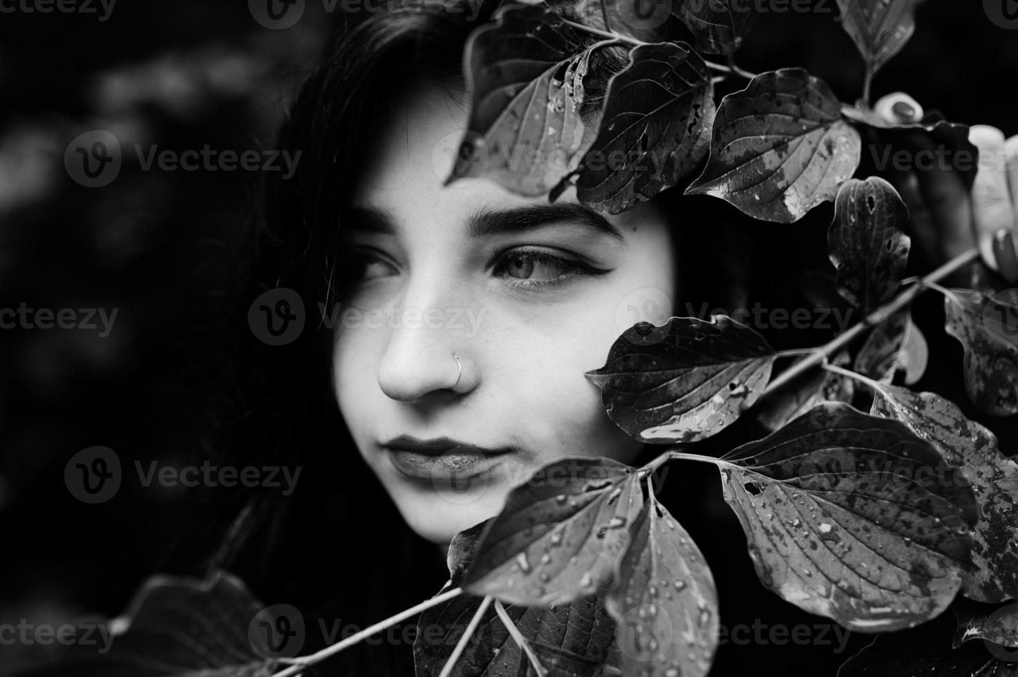Close up portrait of sensual brunette girl with red lips. Goth dramatic woman at tree branch. Black and white. photo