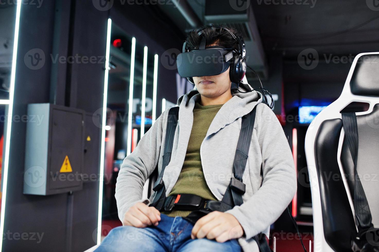 Young indian man having fun with a new technology of a vr headset at virtual reality simulator. photo