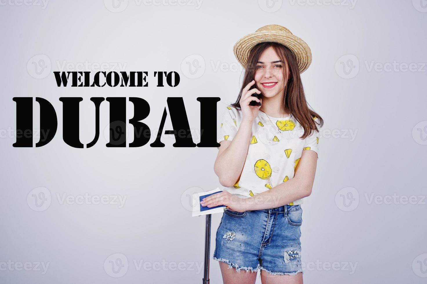 Girl tourist with bag, wear in shirt, shorts and hat, speaking on phone isolated on white. Welcome to Dubai. photo