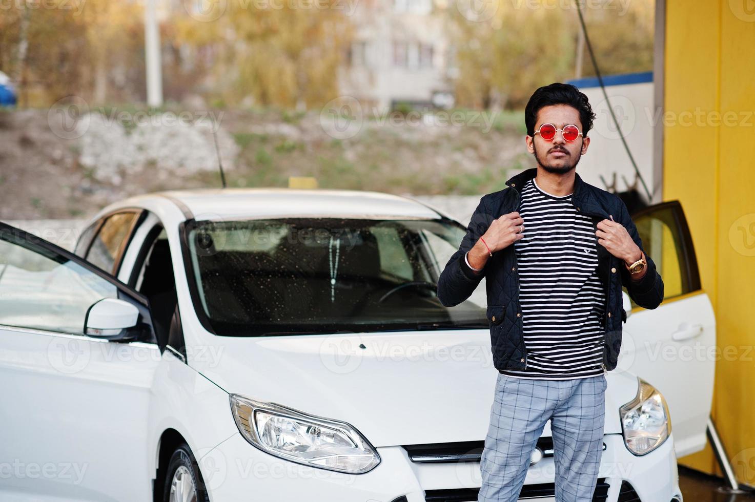 South asian man or indian male washing his white transportation on car wash. photo