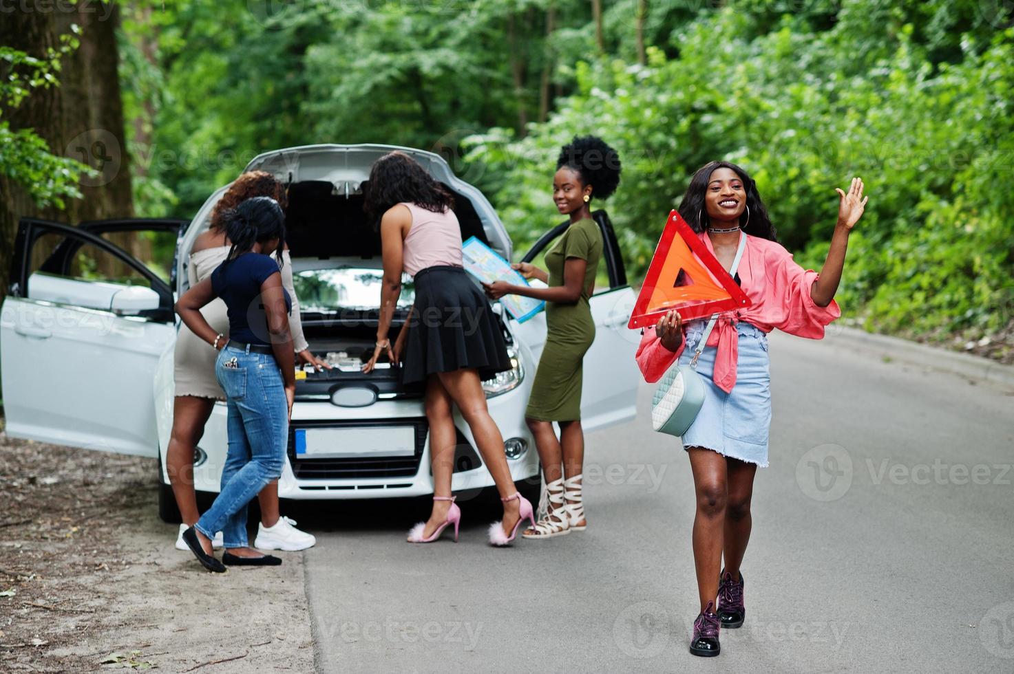 Group of five african american traveler girls looking at broken car open hood. photo