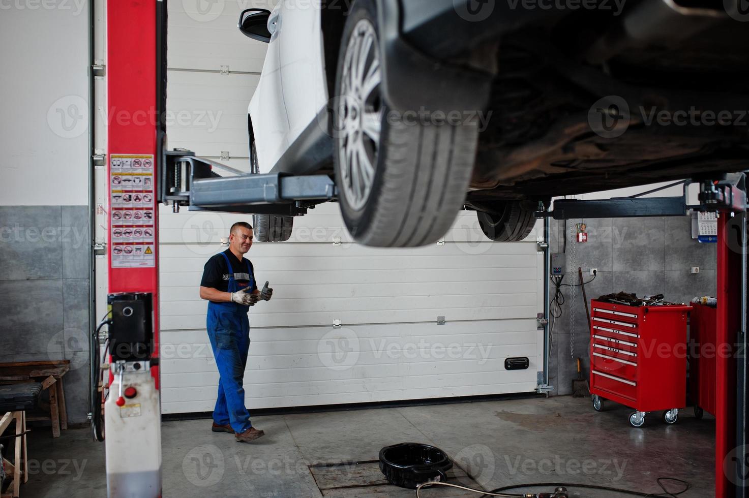 Car repair and maintenance theme. Mechanic in uniform working in auto service. photo