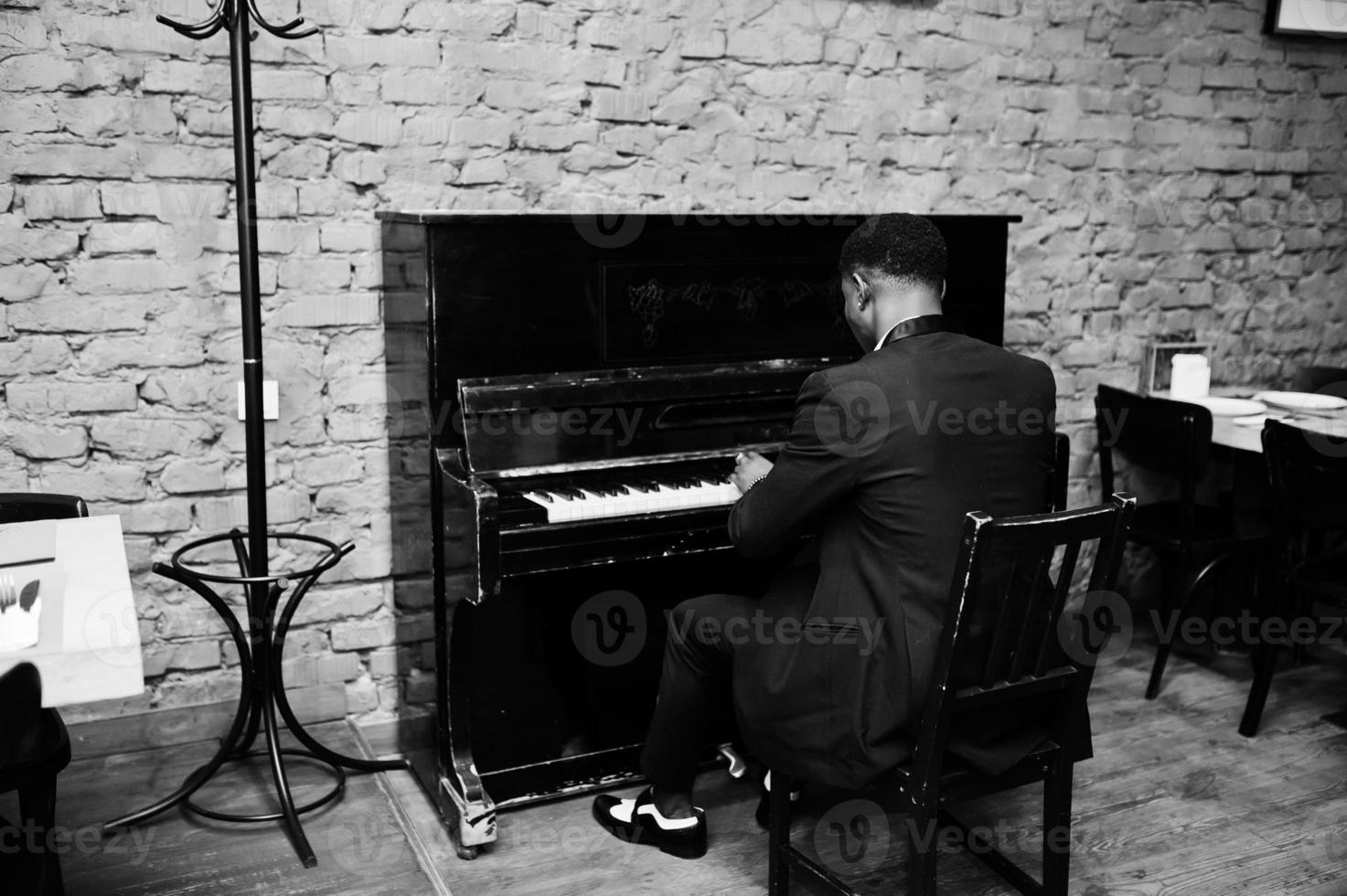 Back of strong powerful african american man in black suit play piano. photo