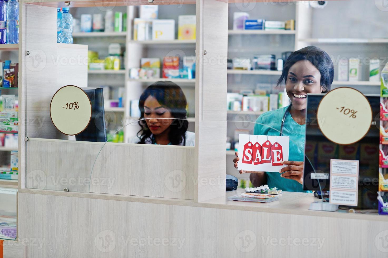 Two african american pharmacist working in drugstore at hospital pharmacy. African healthcare. Cashier holding sale. photo