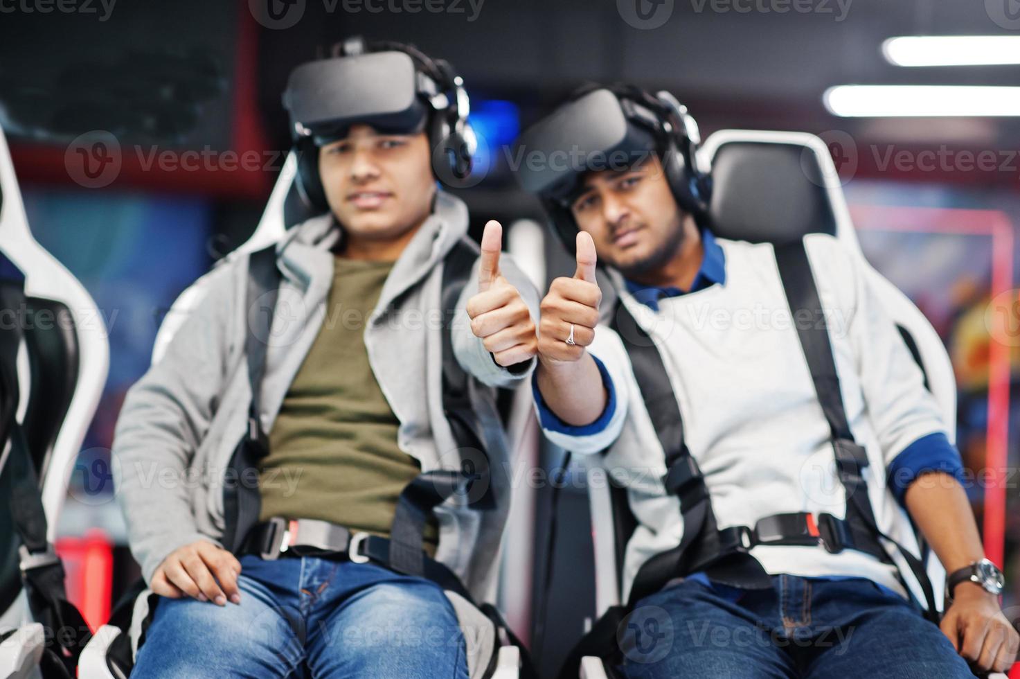 Two young indian people having fun with a new technology of a vr headset at virtual reality simulator. They happy and show thumb up. photo