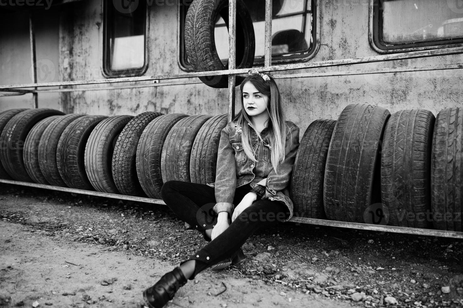 Young hipster girl in jeans jacket and head scarf at tire fitting zone. photo