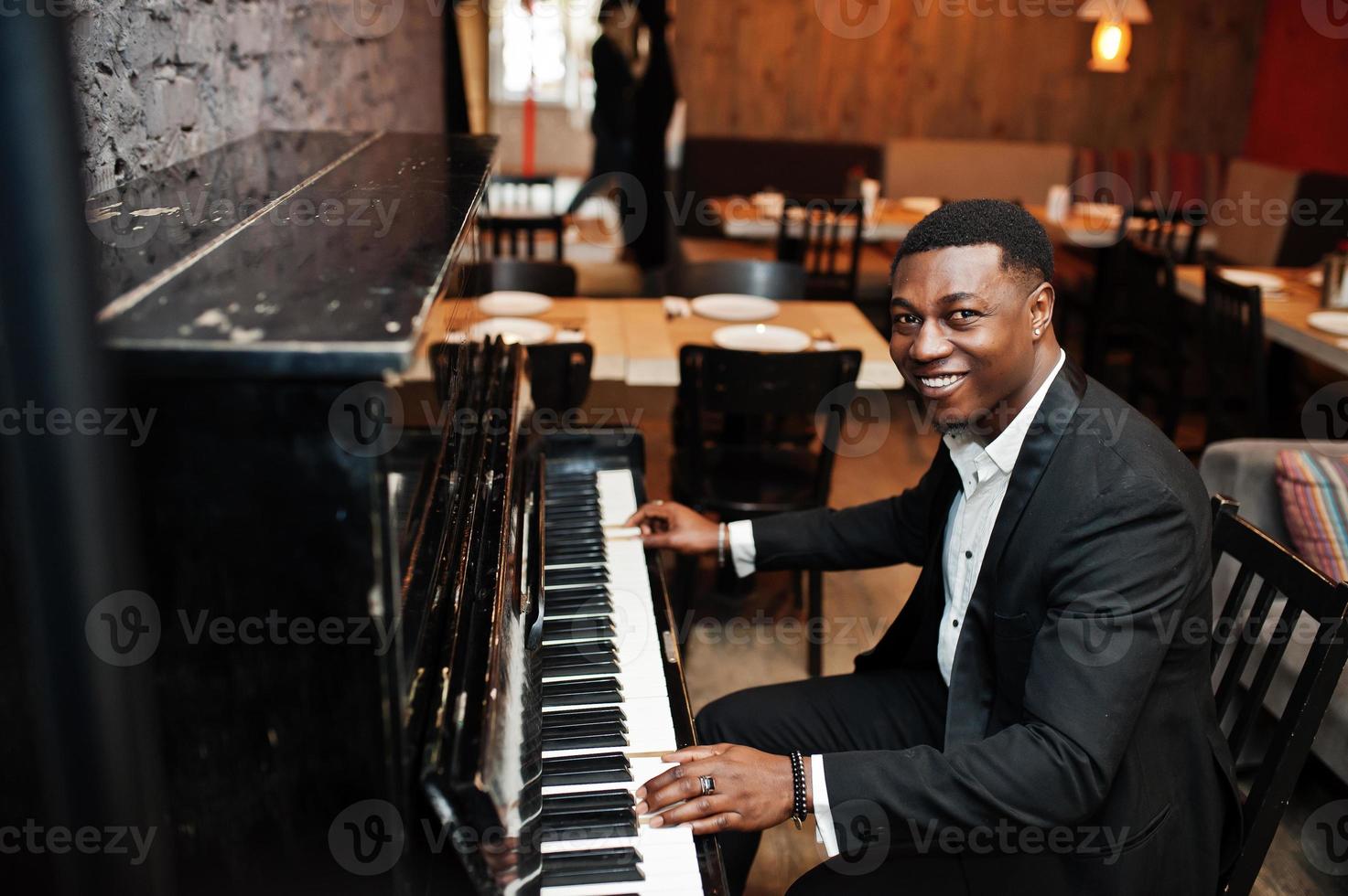 Strong powerful african american man in black suit play piano. photo