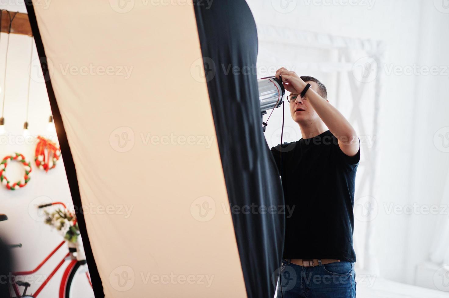 Photographer adjusts the flash light on studio. photo