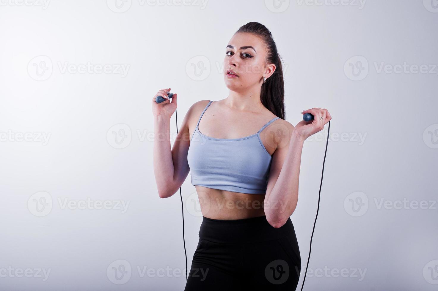 Cheerful attractive young fitness woman in top and black leggings with jump rope isolated over white background. photo