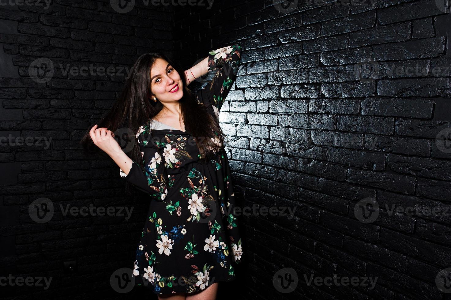 retrato de una joven fabulosa vestida de flores en el oscuro estudio. foto