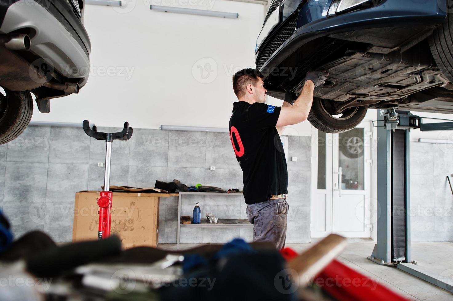 Car repair and maintenance theme. Mechanic in uniform working in auto service. photo