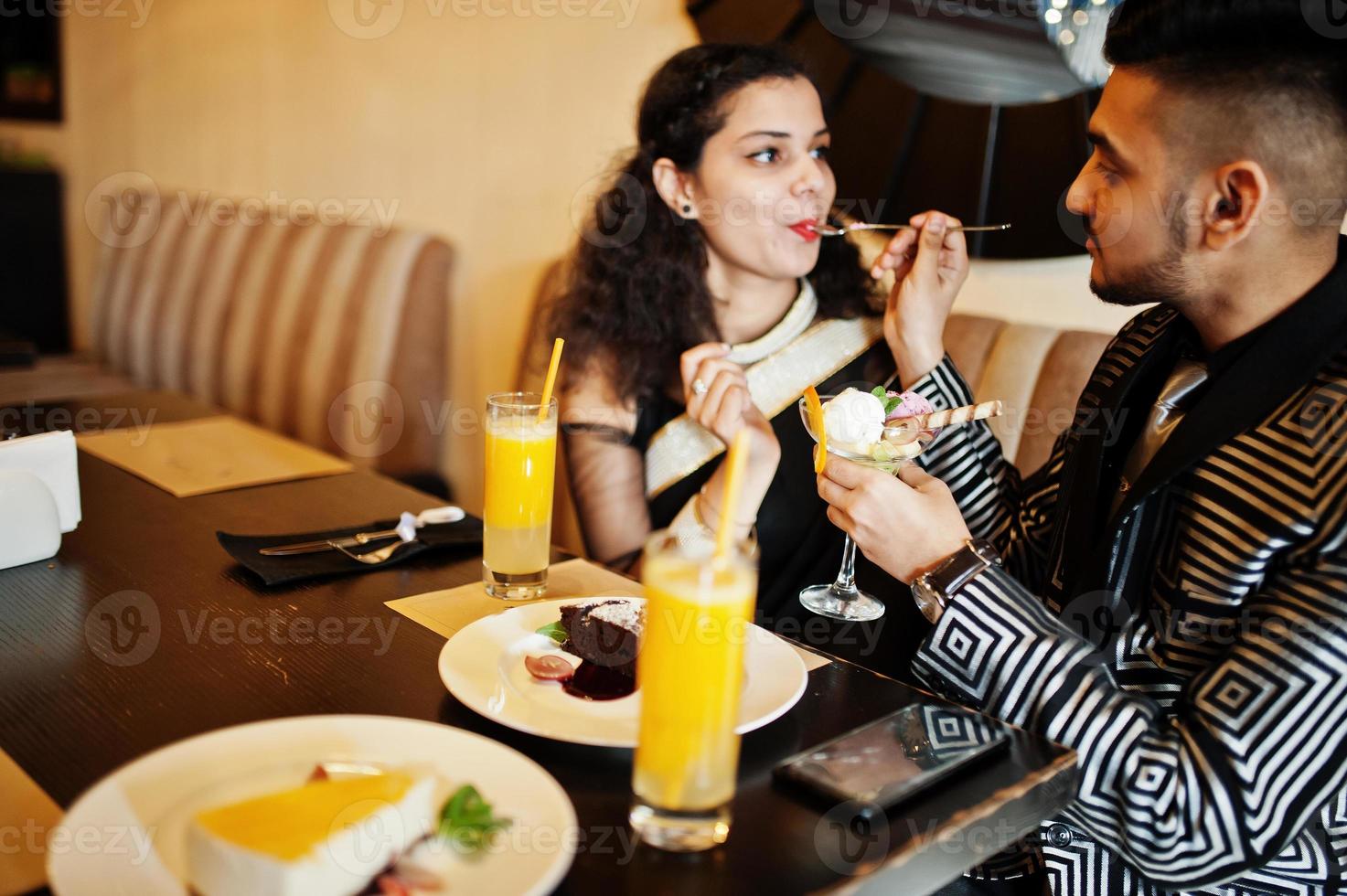Encantadora pareja india enamorada, vestida con sari y traje elegante,  sentada en el restaurante y comiendo helado juntos. 10500779 Foto de stock  en Vecteezy