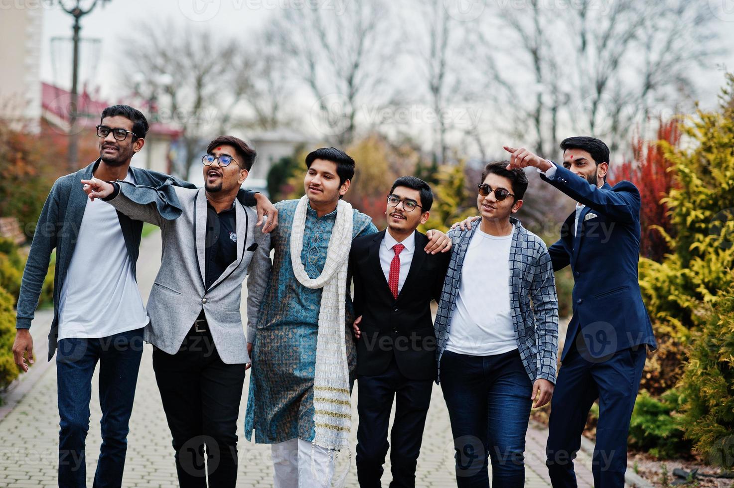 Group of six south asian indian mans in traditional, casual and business wear walking and shows fingers to something. photo