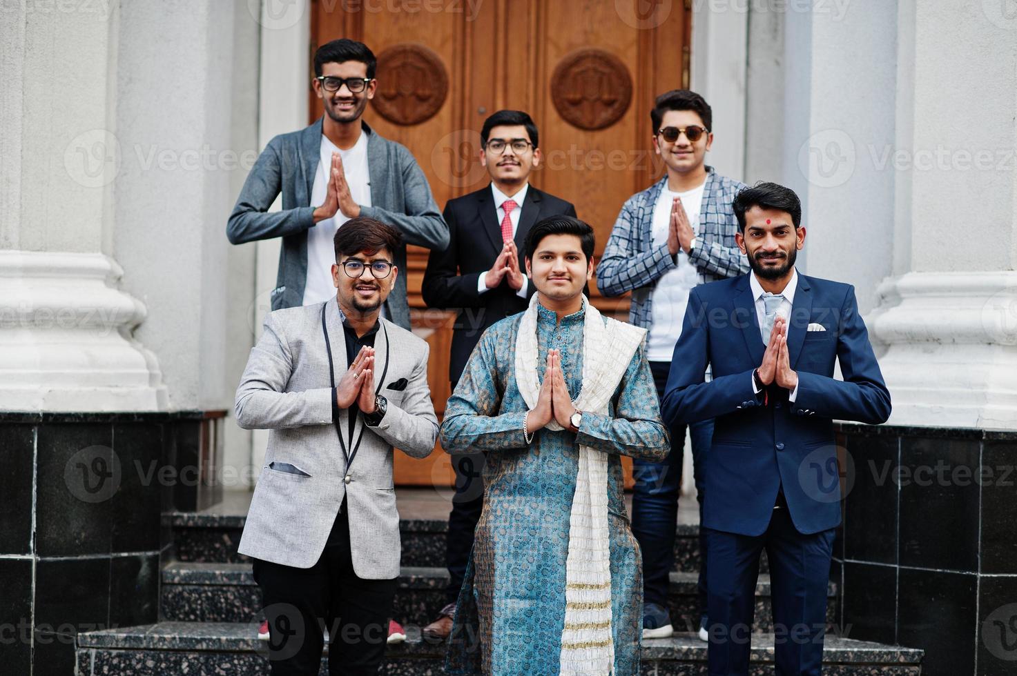 grupo de seis hombres indios del sur de asia con ropa tradicional, informal y de negocios parados en las escaleras y mostrando el signo de las manos de namaste. foto