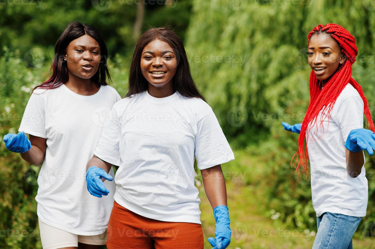 Three african volunteer womans in park. Africa volunteering, charity, people and ecology concept. photo