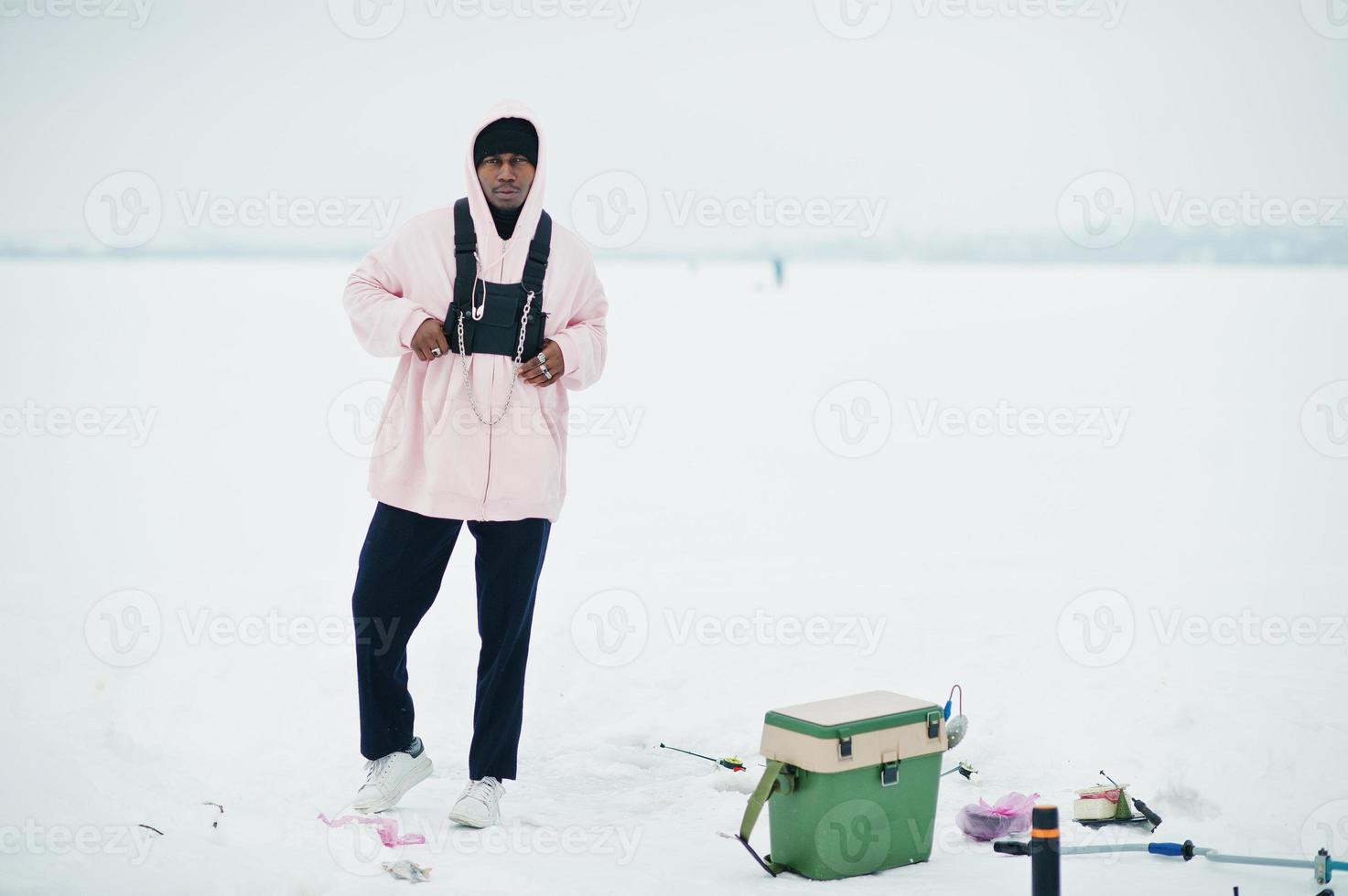 African american fisherman on frozen sea. Winter fishing. photo