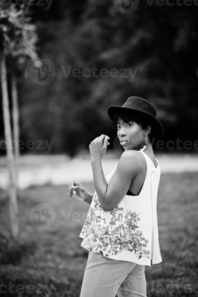 Amazing african american model woman in green pants and black hat posed at park. photo