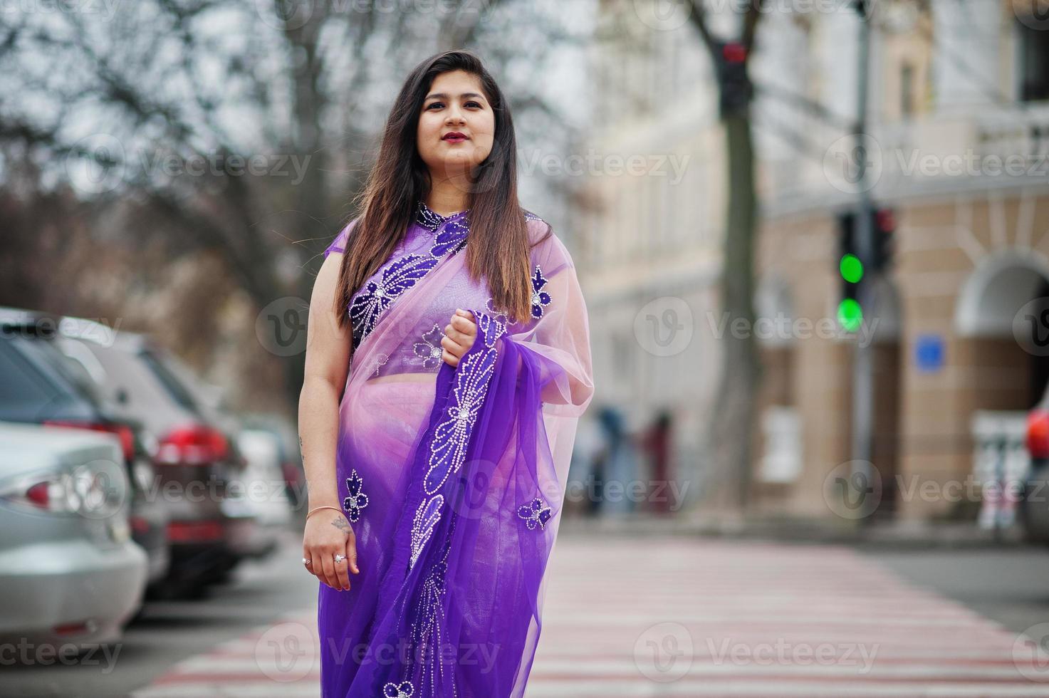 Indian hindu girl at traditional violet saree posed at street , walking at pedestrian crossing. photo