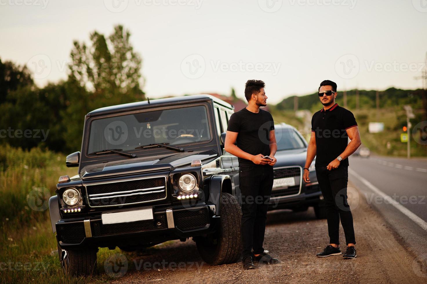 Two asian brothers man wear on all black posed near suv cars. photo