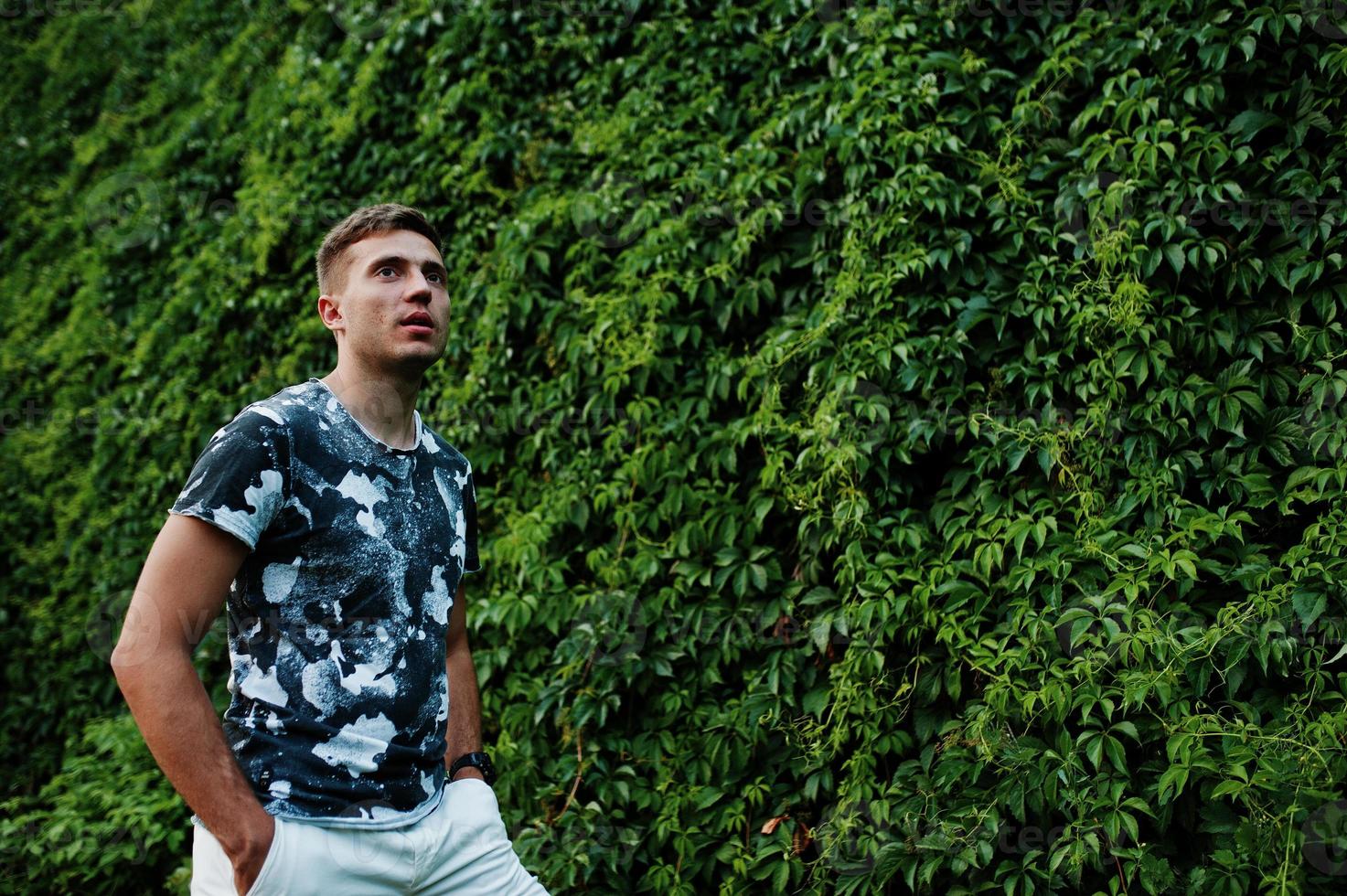 Lifestyle portrait of handsome man posing against greenery wall. photo