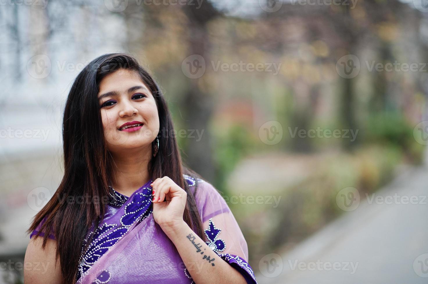 Close up portrait of indian hindu girl at traditional violet saree posed at street. photo