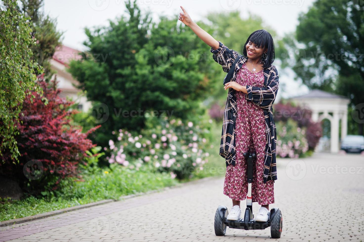 Beautiful african american woman using segway or hoverboard. Black girl on dual wheel self balancing electrical scooter. photo
