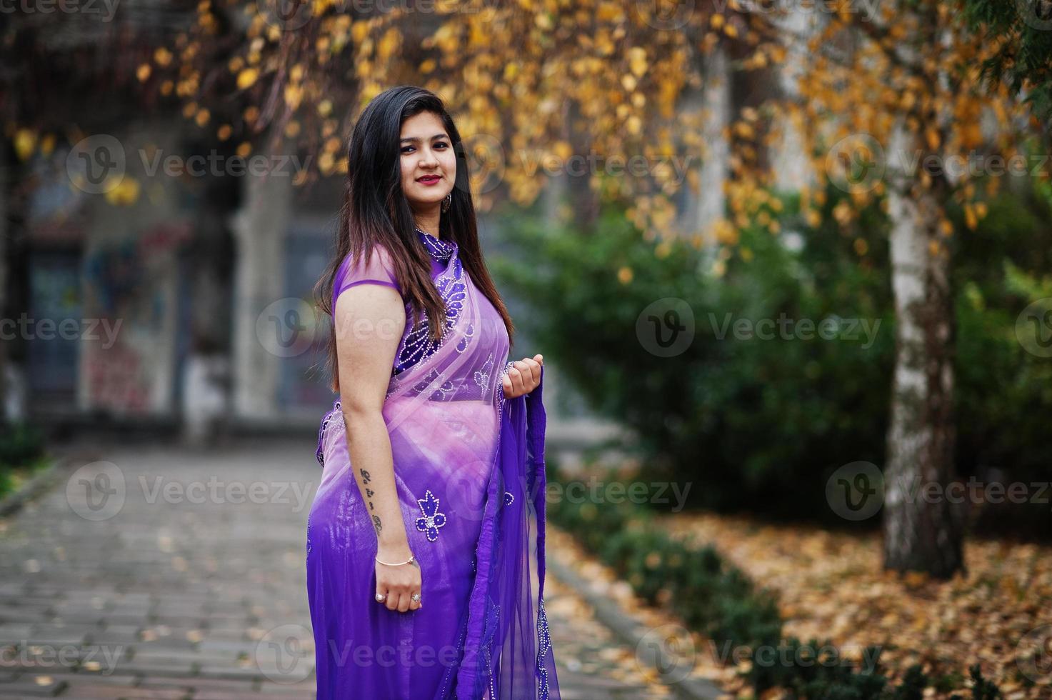 Indian hindu girl at traditional violet saree posed at autumn street. photo