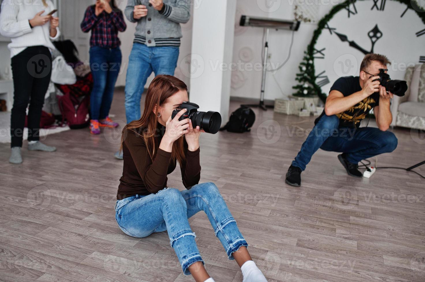 el equipo de dos fotógrafos disparando en el estudio detrás de otros tres trabajadores. fotógrafo profesional en el trabajo. foto