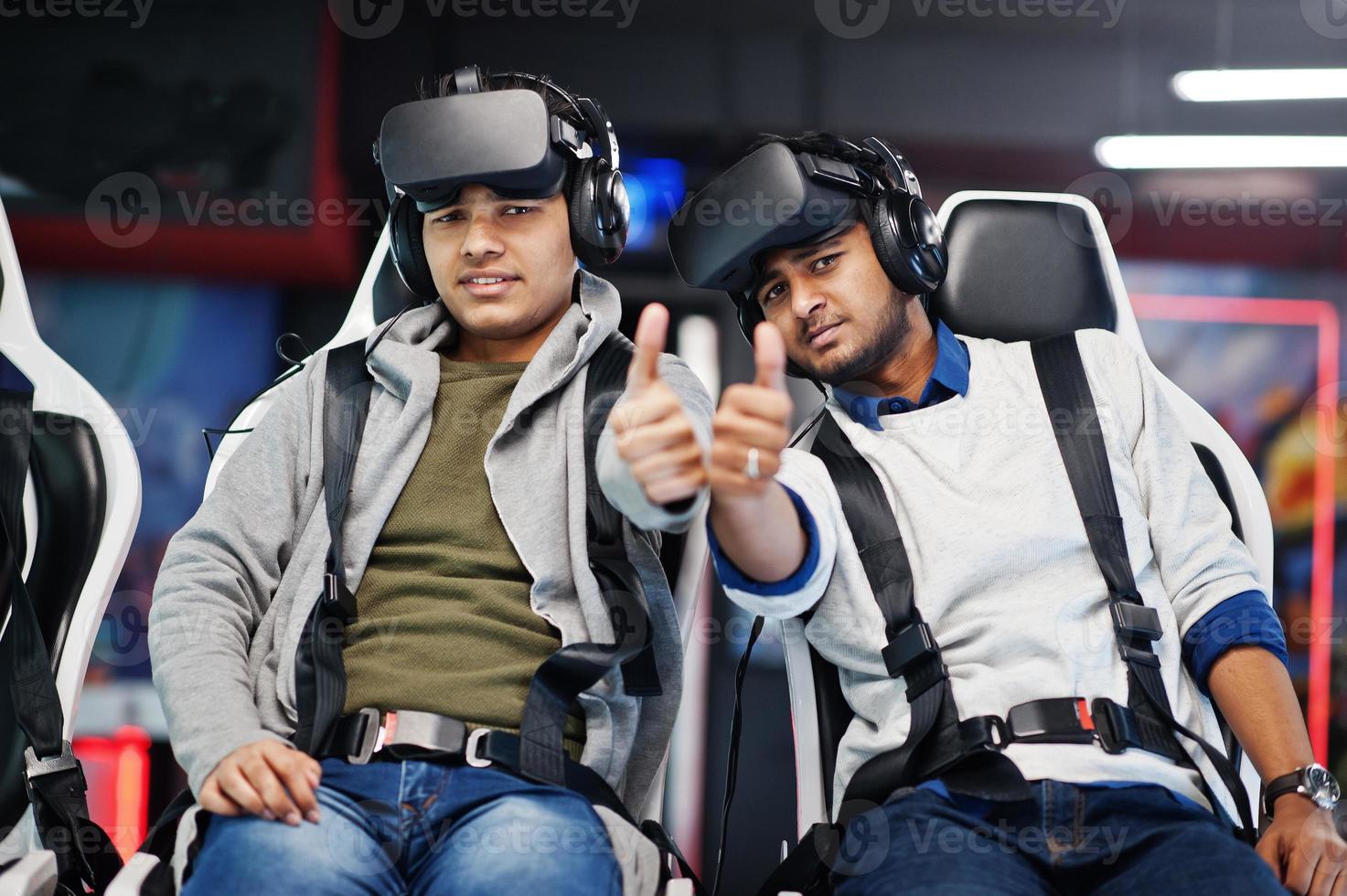Two young indian people having fun with a new technology of a vr headset at virtual reality simulator. They happy and show thumb up. photo