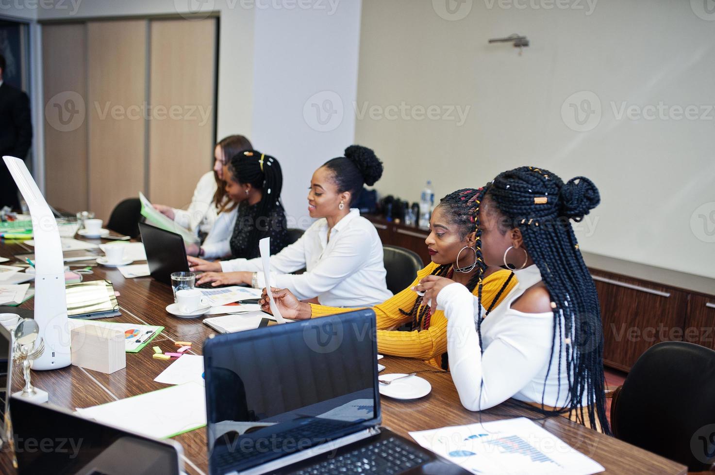 Multiracial women colleagues, crew of divercity female partners in office sit at the table. photo