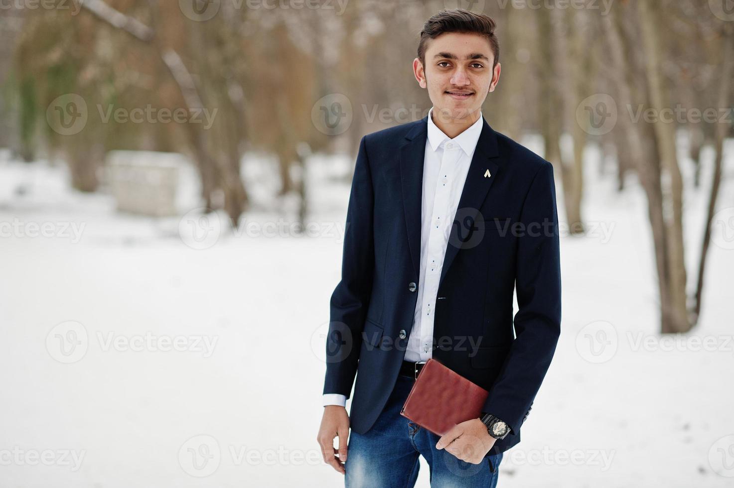 Stylish indian student man in suit posed at winter day outdoor with notebook at hands. photo