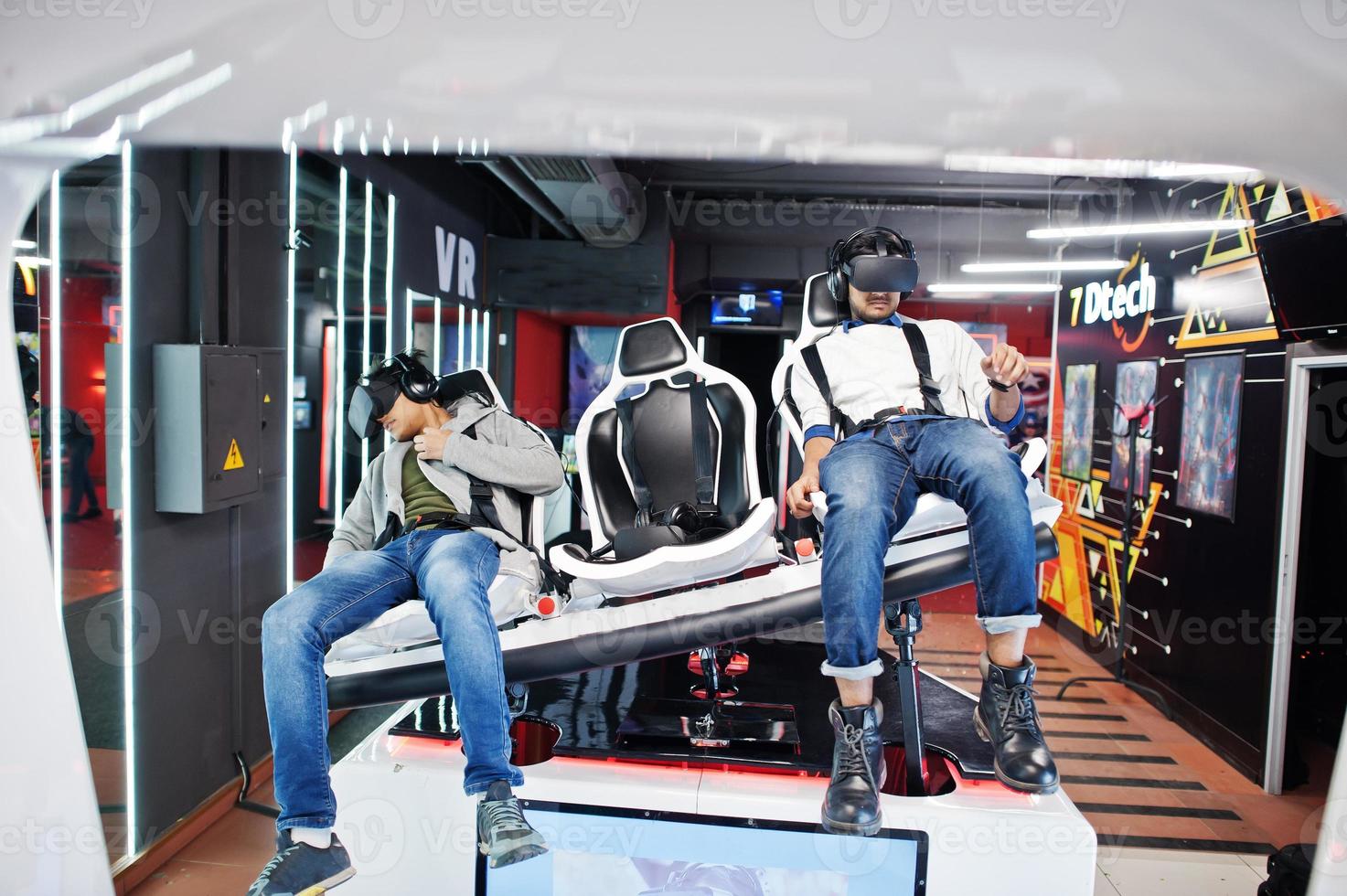 Two young indian people having fun with a new technology of a vr headset at virtual reality simulator. photo