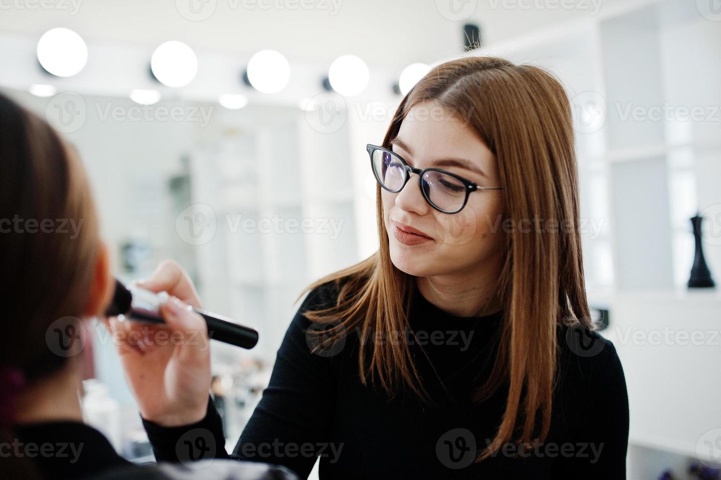 Make up artist work in her beauty visage studio salon. Woman applying by professional make up master. Beauty club concept. photo