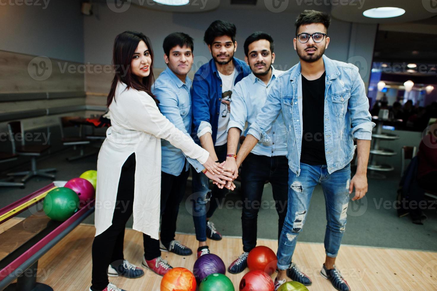 Group of five south asian peoples having rest and fun at bowling club. Putting their hands together, friends showing unity and teamwork. photo