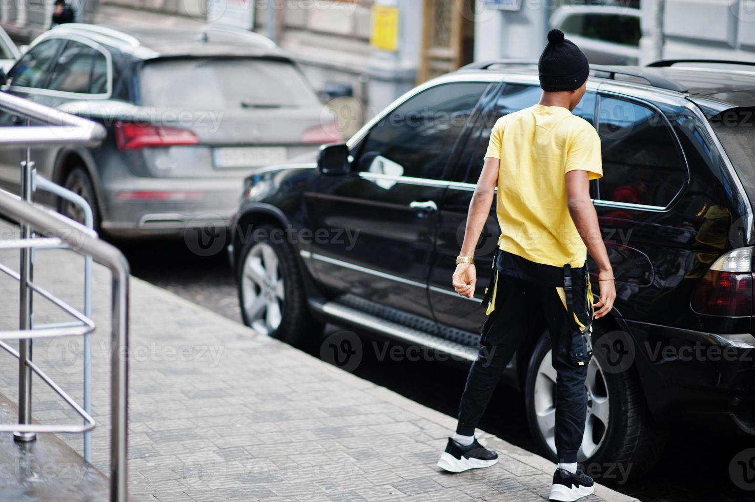 African man wear on black hat posed outdoor against business car. photo